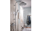 Chrome rain shower and hand shower in a modern bathroom with light tiles.
