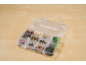 Open clear plastic organizer box with various rotary tool accessories on a wooden surface.