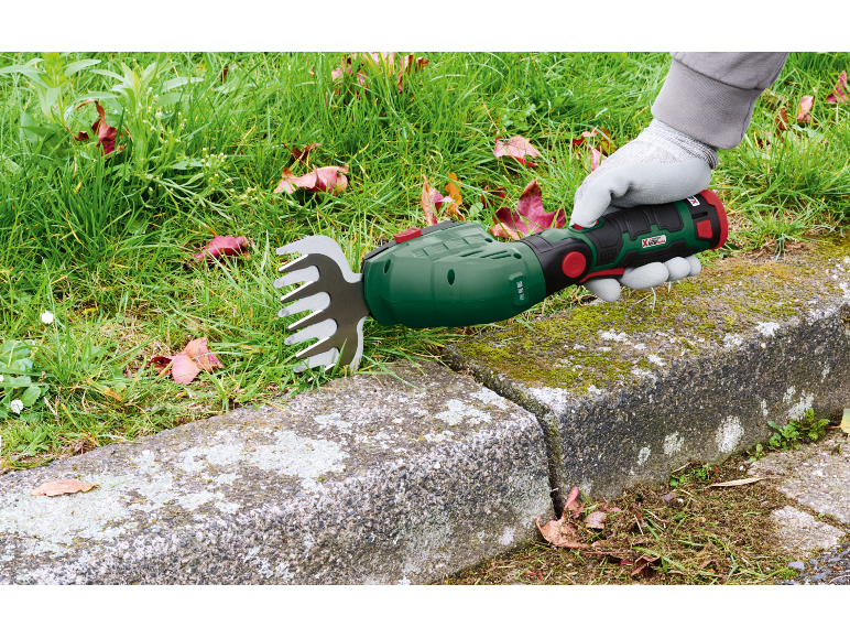 Handheld grass trimmer cutting grass along a concrete curb.