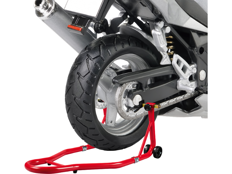 Rear view of a motorcycle on a red stand, showing the tire, chain, and exhaust.