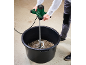 Person mixing concrete in a black bucket with an electric mixer.