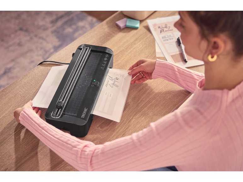 Woman laminating a weekly planner on a wooden table.