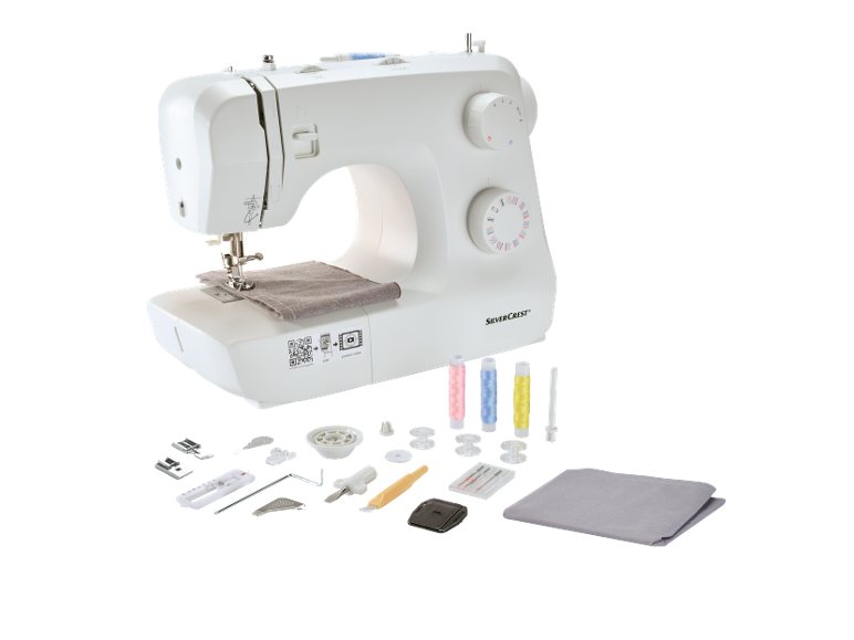 White sewing machine with fabric and various sewing accessories.