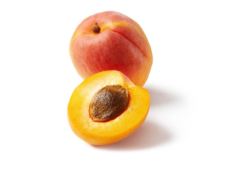A whole apricot and a halved apricot with a pit on a white background.