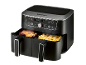 Black dual-basket air fryer cooking chicken and fries, with a digital display.