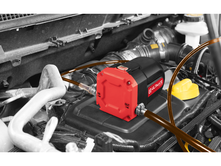 Oil pump in a car engine, with red and black housing and connected hoses.