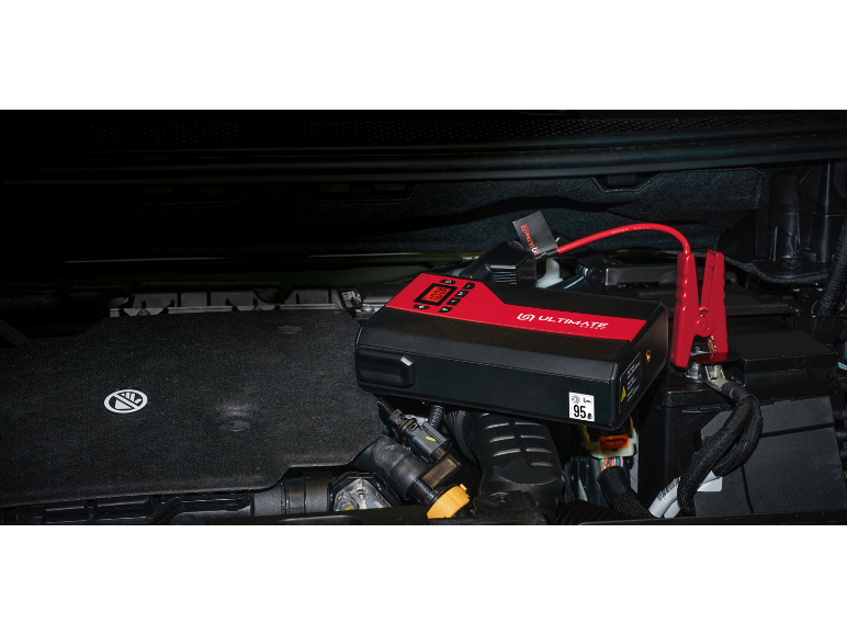 Portable jump starter and battery charger in a car engine.