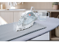 Steam iron on ironing board with water measuring cup.