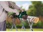 Person in gloves using a chainsaw to cut wood on a sawhorse.