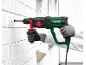 Man drilling a hole into a white brick wall with a rotary hammer.