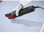 Gloved person uses an electric tool to cut into a blue surface.