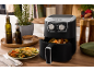 Air fryer with roasted vegetables, oil bottles, and spices in a kitchen setting.