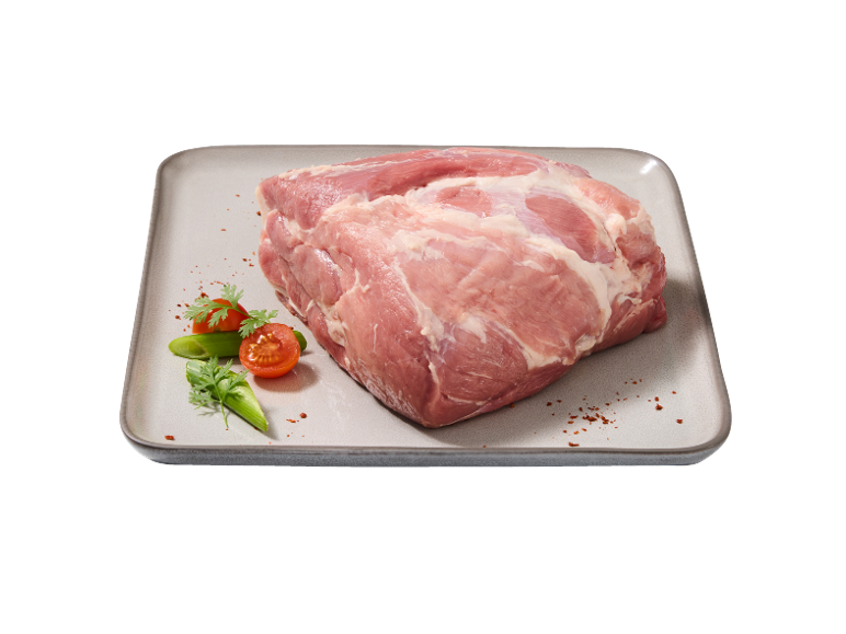 Piece of raw pork meat, garnished with tomatoes and vegetables on a platter.
