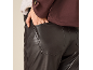 Detail of a woman in brown faux leather trousers and a burgundy jacket.