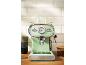 Light green espresso machine with chrome details and a temperature gauge on a wooden countertop.