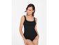 Woman in a black lace-trimmed camisole and black briefs, smiling.