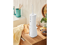 White oral irrigator in a bathroom with a yellow towel and wooden comb.