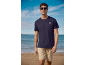 Man in navy t-shirt with compass logo and beige shorts on a beach.