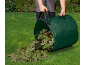 Man emptying a green garden waste bag full of leaves onto a lawn.