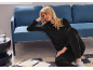 Woman in black tracksuit sitting on the floor next to a blue sofa, with an open notebook.