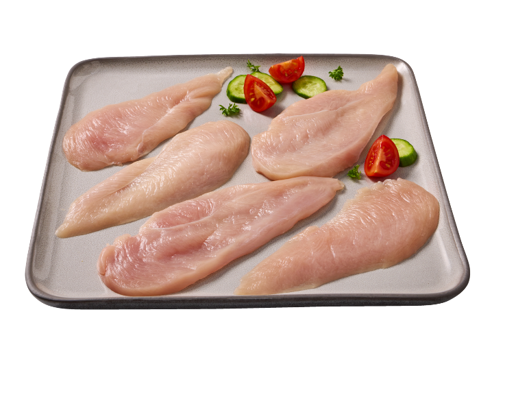 Raw chicken fillets with cherry tomatoes and cucumbers on a tray.