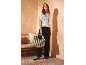 Woman in white open-knit shirt, black trousers, black ballet flats, and striped bag.