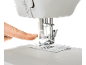 Close-up of a sewing machine with a finger pressing the needle threader.