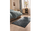 Bedroom with a bed, blue rug, and wooden cabinet next to the window.