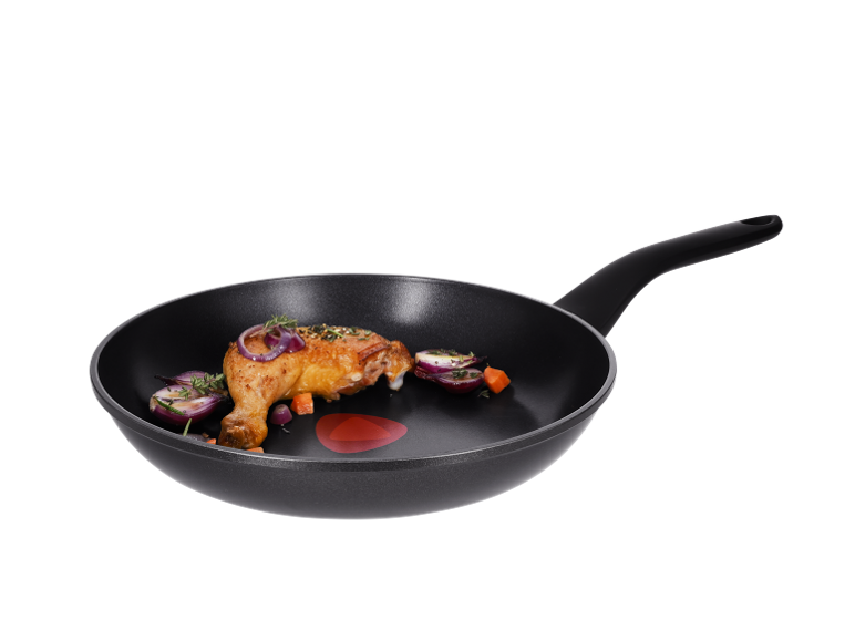 Roasted chicken leg with onion and carrot in a frying pan.