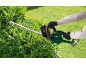Gloved person trimming a hedge with a cordless hedge trimmer.