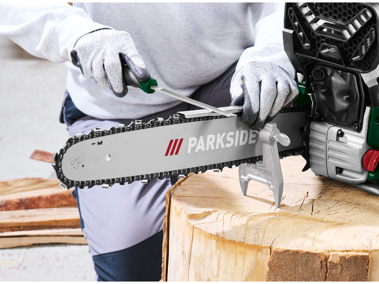 Sharpening a chainsaw chain with a file, secured by a vise.