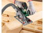 Person cutting a wooden board with a circular saw, connected to a dust extraction hose.