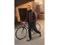Man in black puffer vest, maroon sweatshirt, and cargo pants with a bicycle.