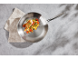 Frying pan with chicken and vegetables on a concrete background with a kitchen towel.
