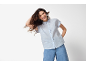 Woman in light blue striped short-sleeved linen shirt and wide-leg jeans.
