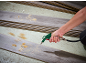 Hand with compressed air gun cleaning wooden floorboards.