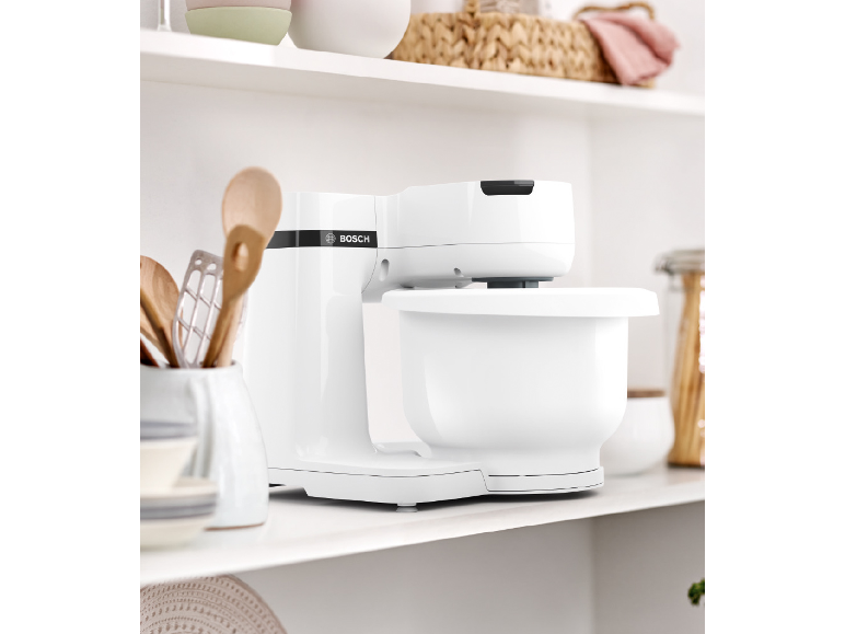 White kitchen machine on a kitchen shelf with wooden utensils.