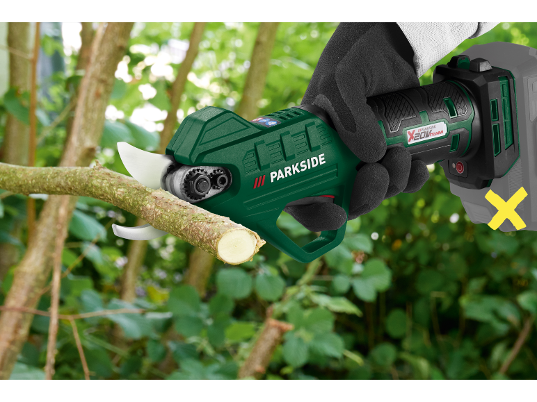 Cordless pruning shears in a hand, cutting a branch.