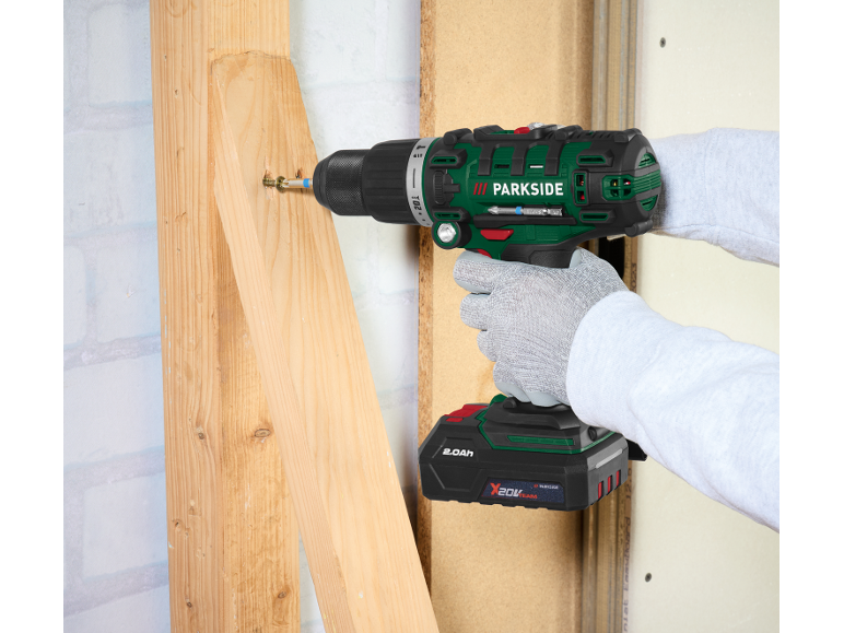 Cordless drill driving a screw into a wooden beam.