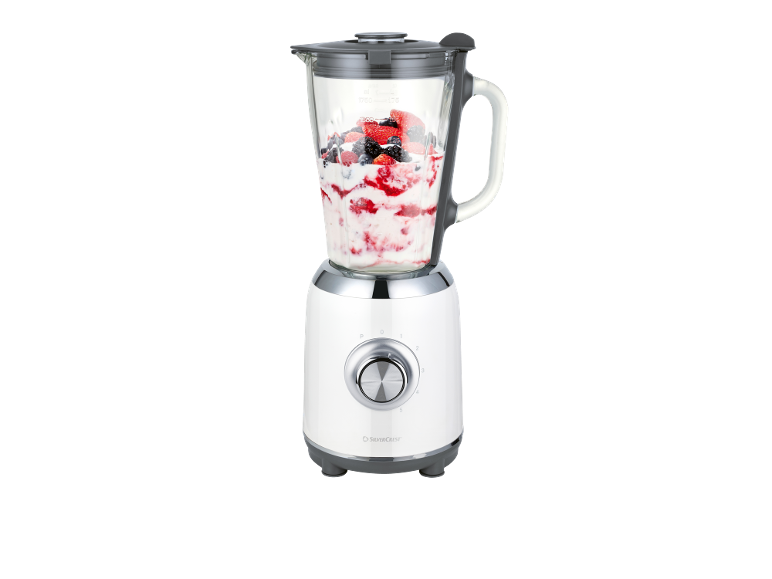 White blender with a glass jar filled with berries and yogurt.