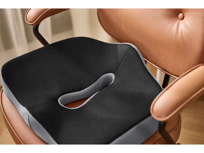 Black and grey orthopedic seat cushion on a brown leather chair.