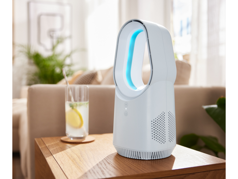 Bladeless fan and a glass of lemonade on a wooden table in a living room.