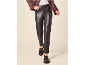 Woman in dark leather trousers, brown jacket, and tassel loafers