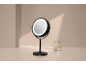 Black illuminated makeup mirror and cotton swabs on a beige background.