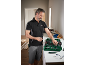 Man in workwear selecting tools from a tool kit on a workbench.