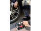 Man inflating a car tire with an air compressor.