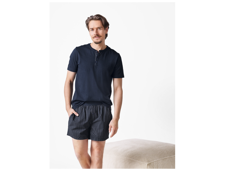 Man in a dark blue short-sleeved T-shirt and striped boxer shorts.
