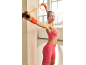 Woman in pink sports top and shorts exercising with a resistance band.