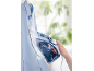 Steam iron ironing a blue shirt, held in hand.