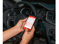 A person in a car holds a smartphone with a car diagnostic application.